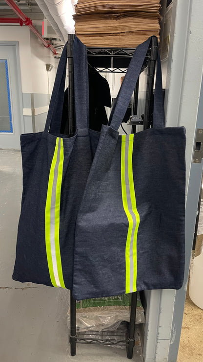 Two dark blue tote bags with reflective yellow stripes hanging on a rack.