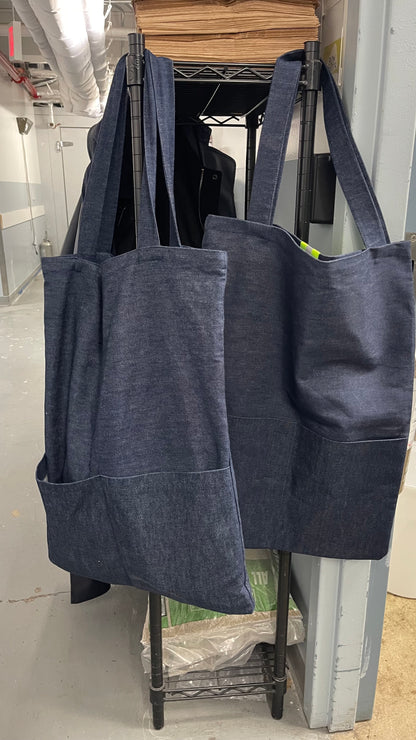 Two dark blue tote bags hanging on a rack in an indoor setting.